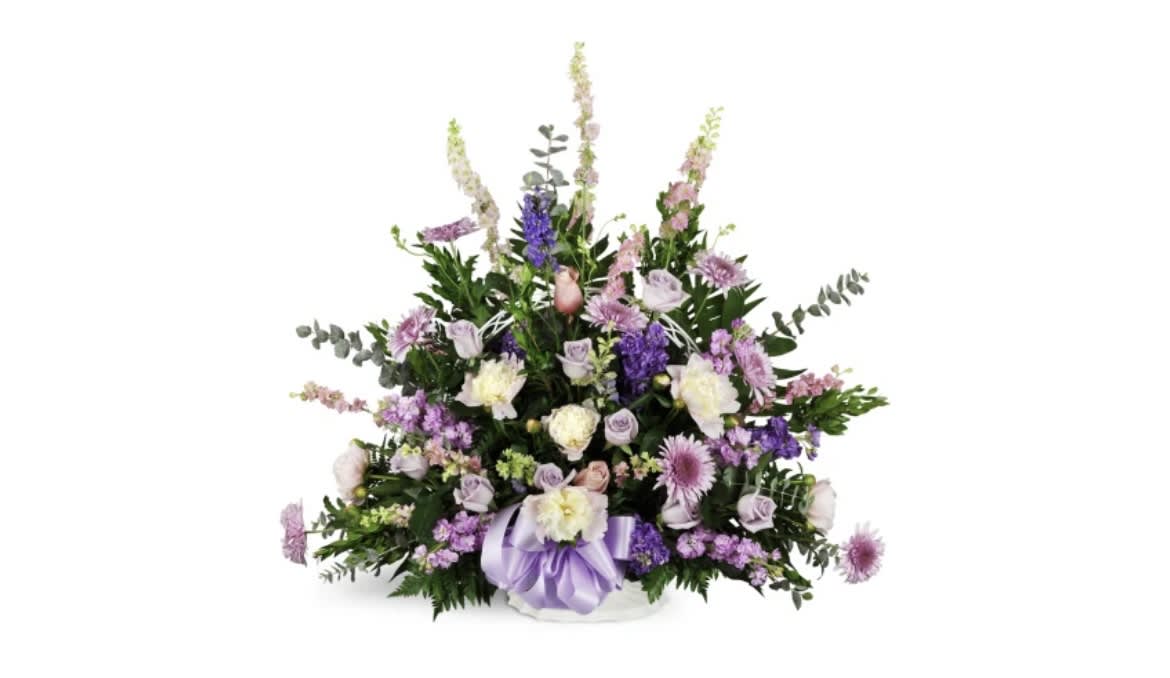 Lavender and white floral arrangement in a white basket with a purple ribbon