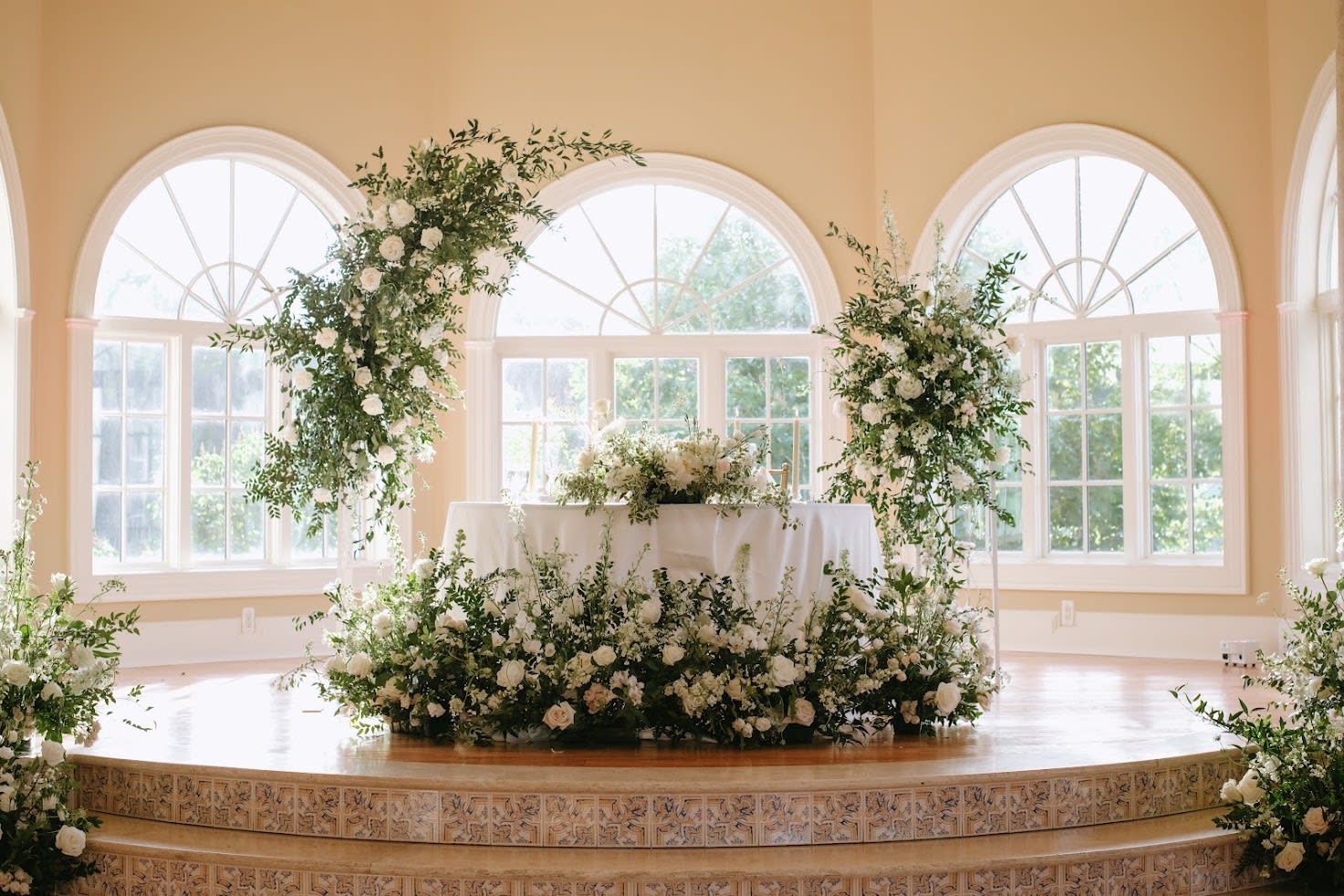 White floral wedding ceremony decor with greenery on a stage
