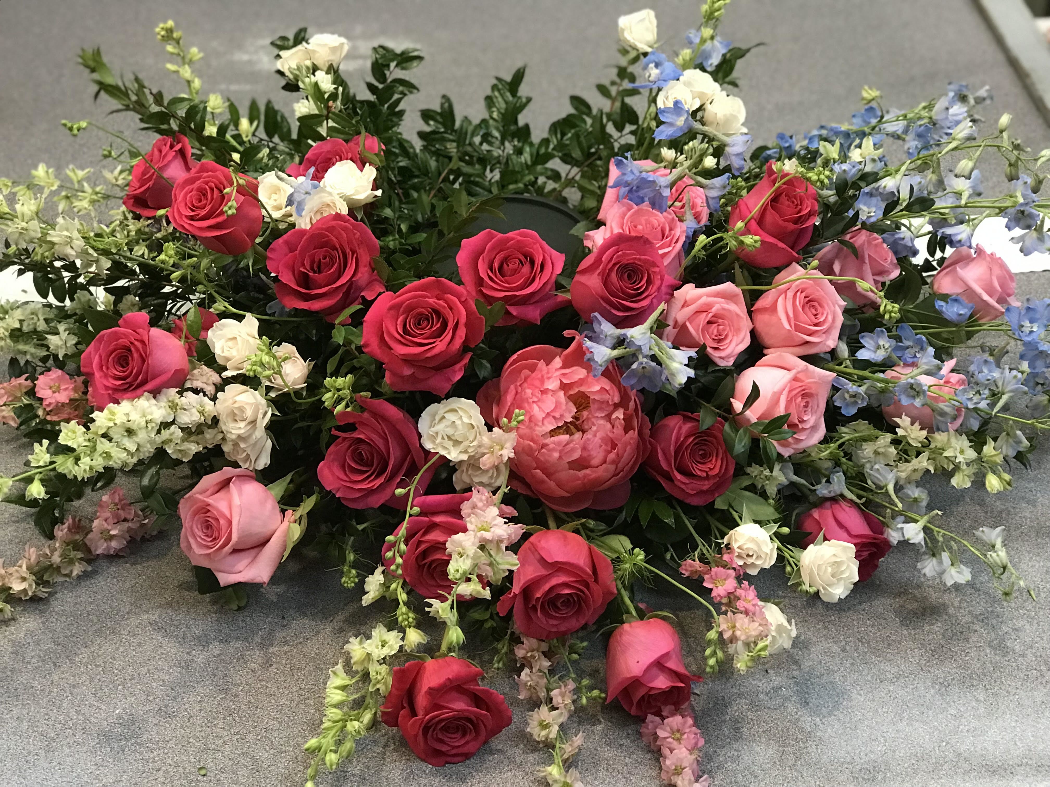 Loose floral arrangement of pink and red roses with blue accents