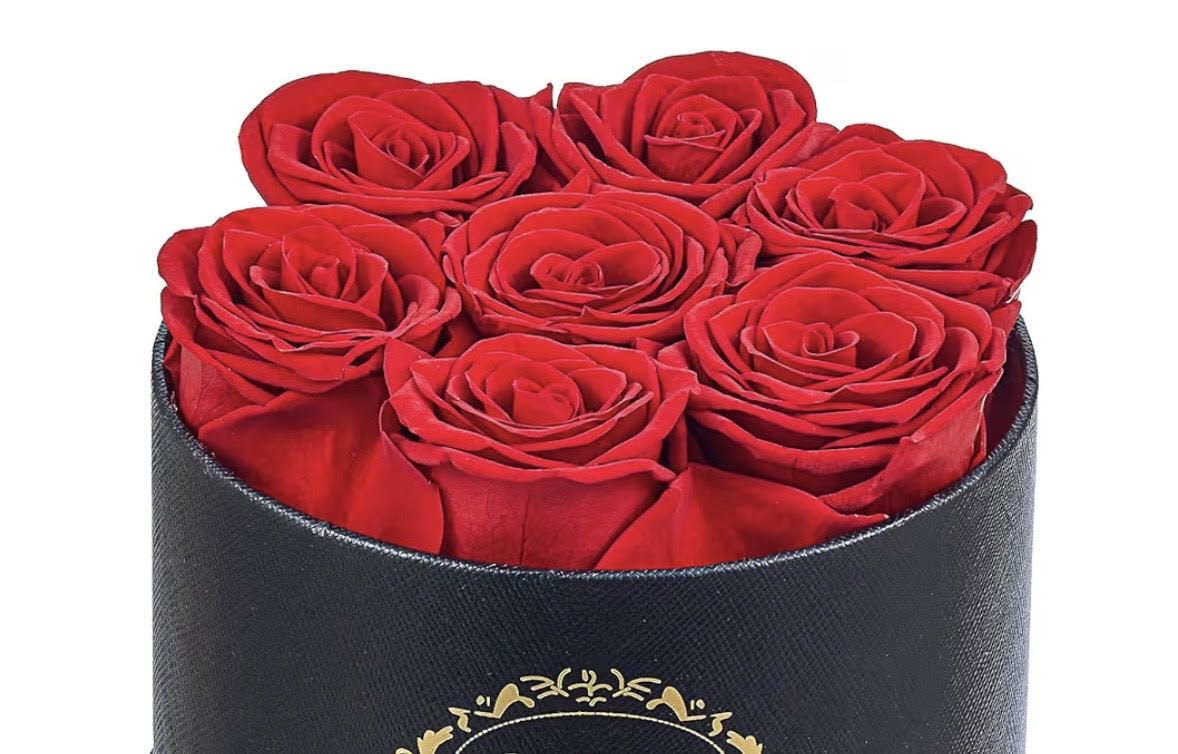 Round black hatbox filled with tightly packed red roses viewed from above
