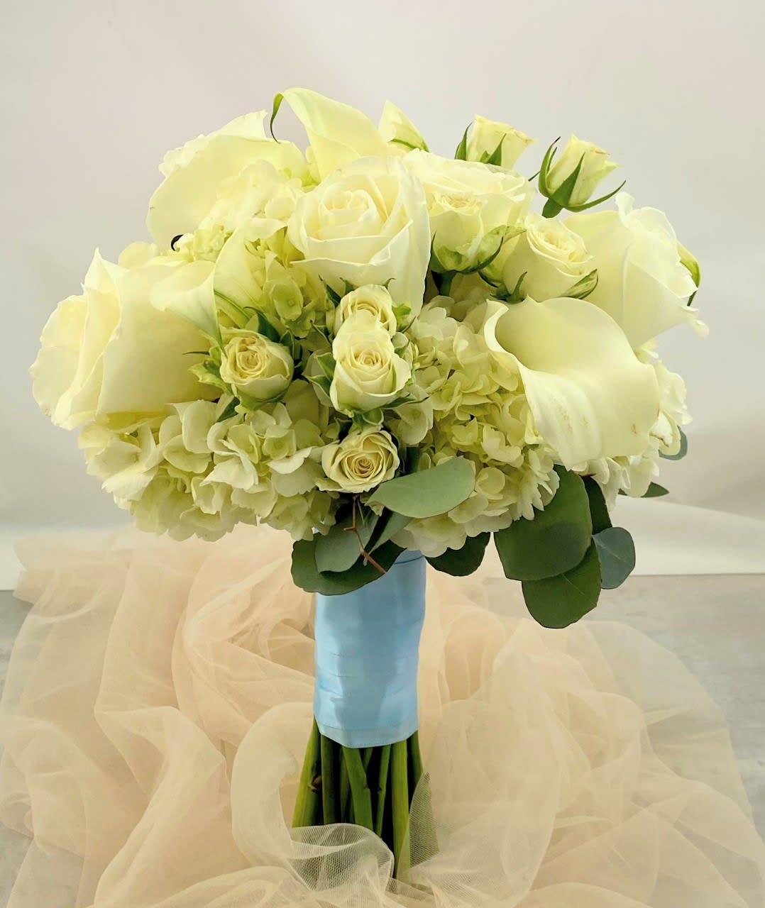 White rose and hydrangea bouquet with calla lilies and blue ribbon wrap