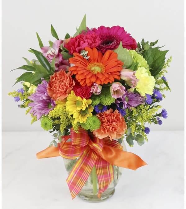 Colorful mixed flower bouquet in a glass vase with ribbon