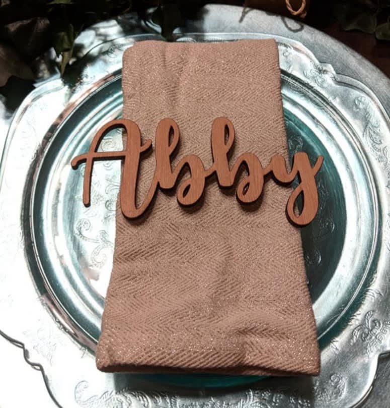 Folded napkin with a wooden "Abby" place card on a silver charger
