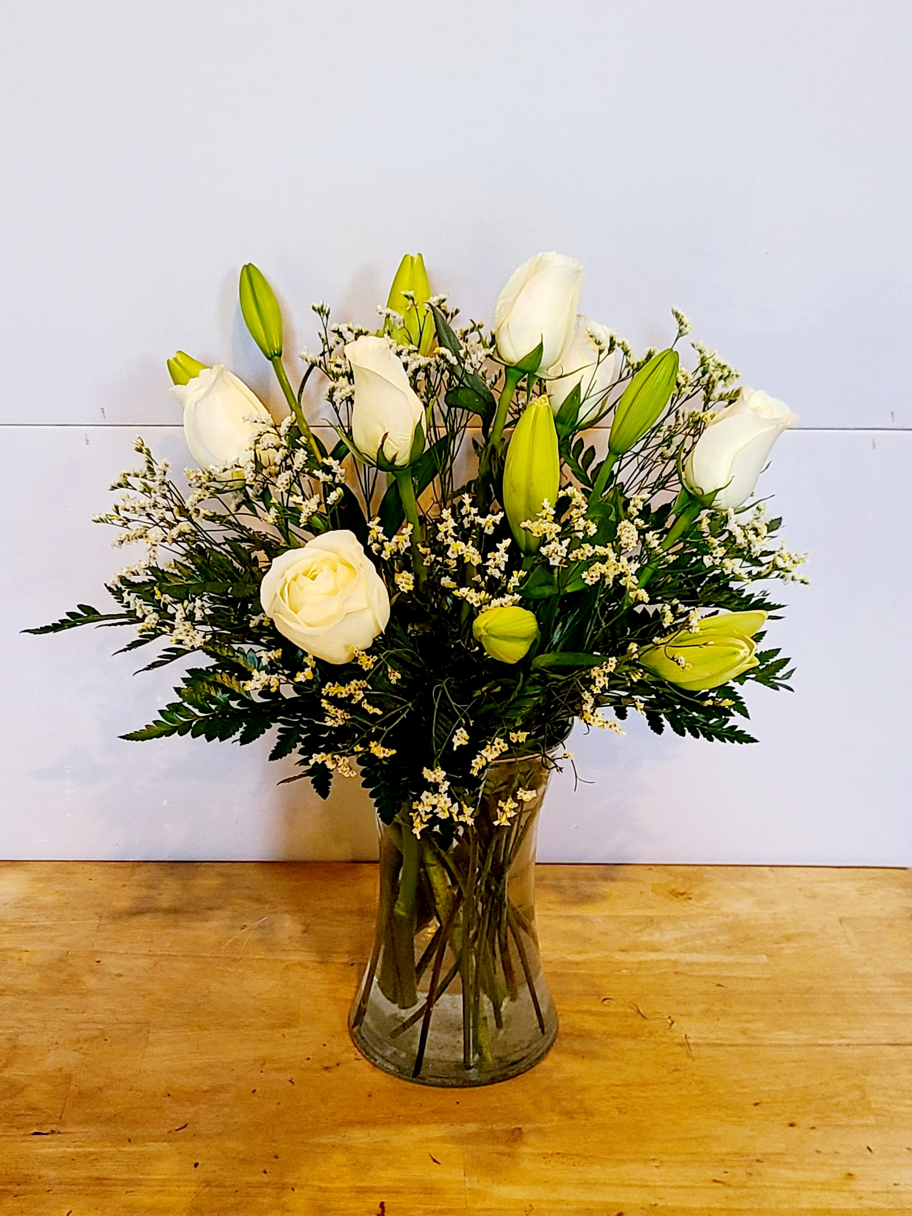 Eternal Love Bouquet - Express your condolences for the loss of a loved one with the Eternal Love bouquet. Brilliant white roses, monte casino, and Asiatic lilies are hand-arranged in a clear glass gathering vase. Topped off with a decorative ribbon, this bouquet will offer your recipient a bit of peace.