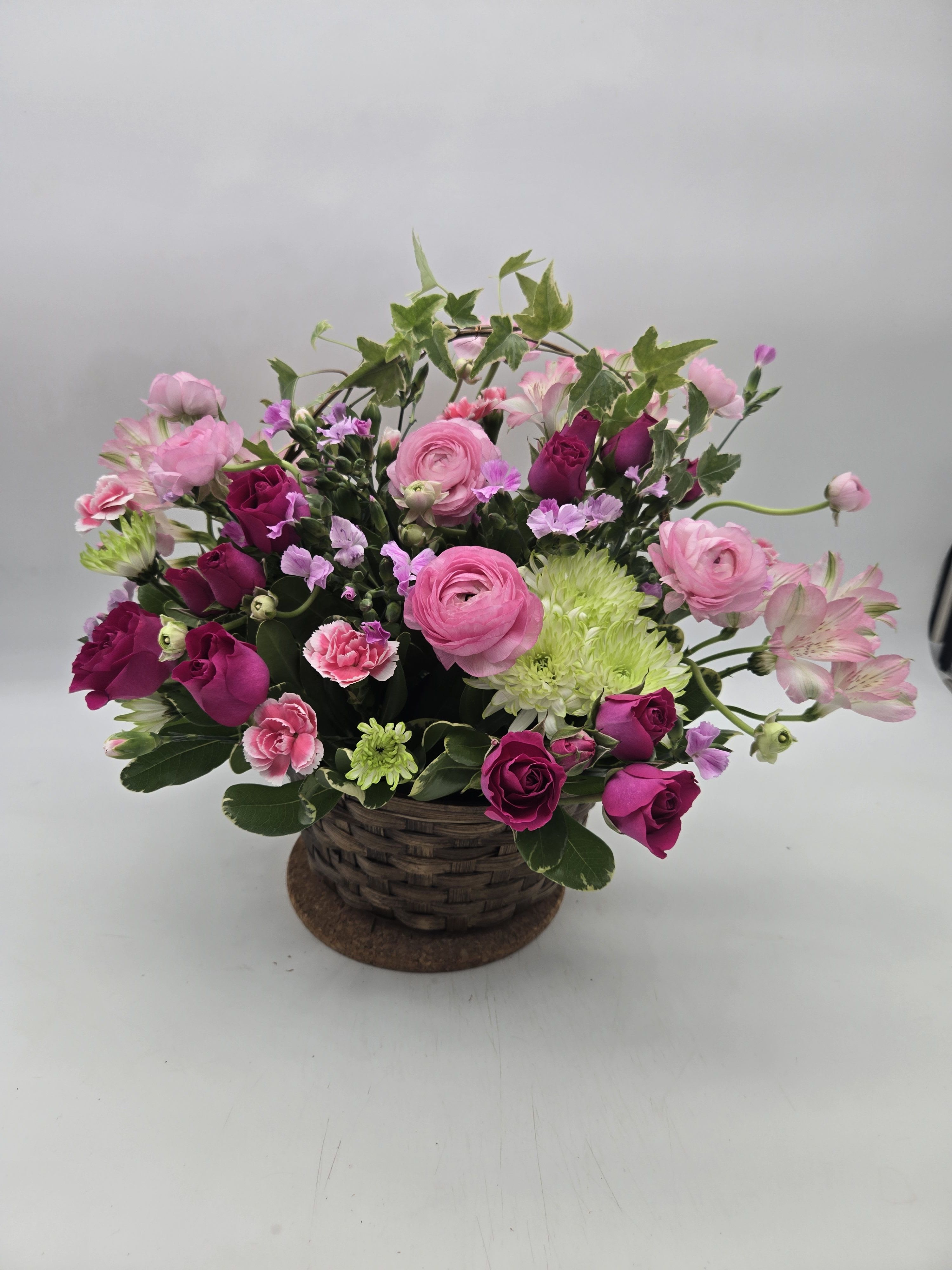Fairest of All - You won't need a mirror, mirror on the wall to decide which bouquet is the fairest of all. No doubt this beauty will win that contest!    Light orange roses, hot pink roses light pink alstroemeria, ranunculas and matsumoto asters, green button spray chrysanthemums and more are delightfully delivered in a charming ivy handled woven basket. Send one to your fair lady!    Approximately 18" W x 14" H    Orientation: All-Around    As Shown : T147-3A  Deluxe : T147-3B  Premium : T147-3C