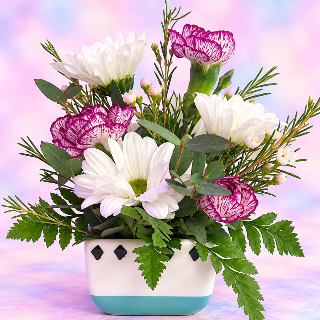 White daisies and purple carnations in a white ceramic vase