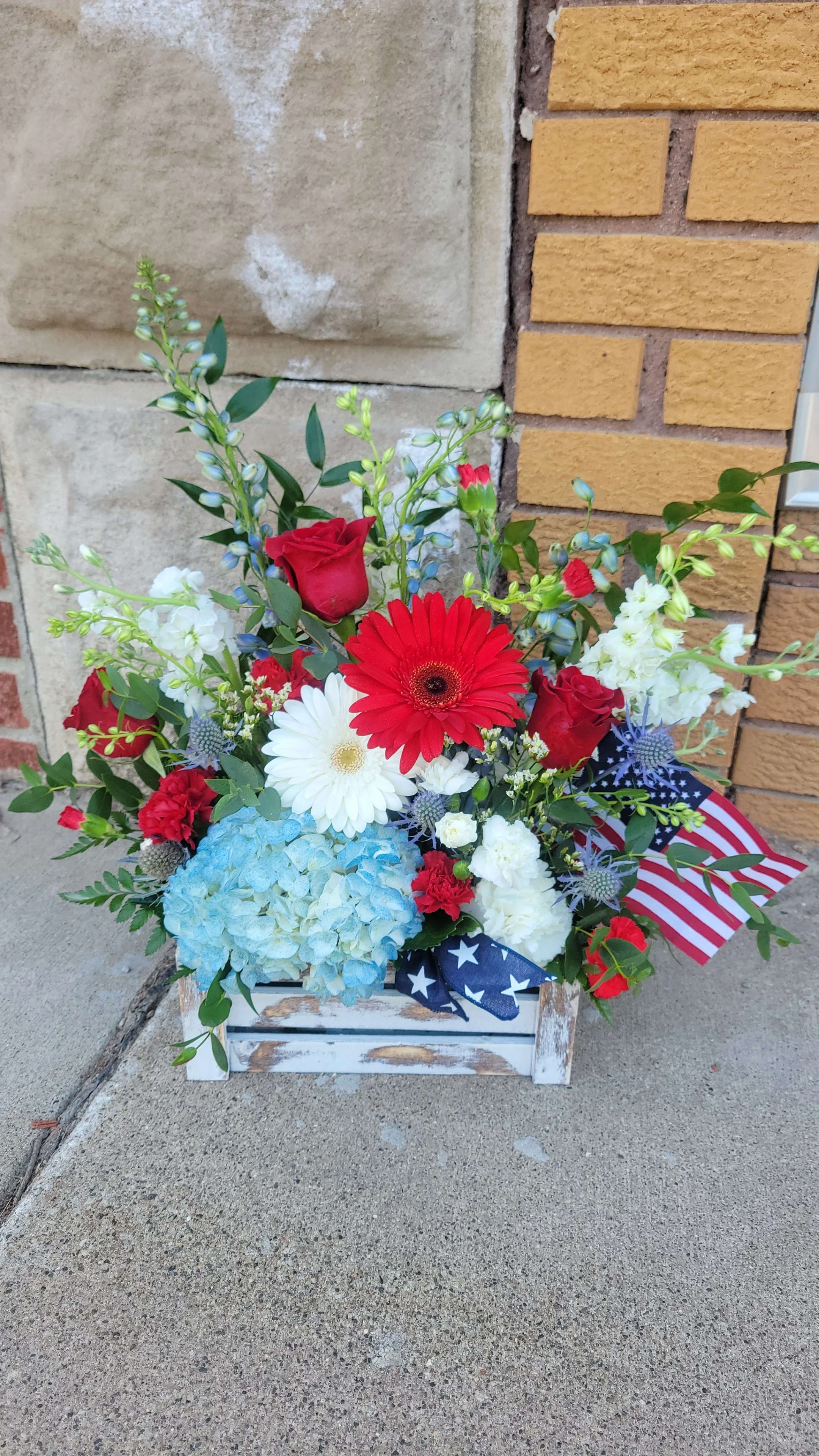 Mixed red, white, and blue floral arrangement in a rustic wooden box