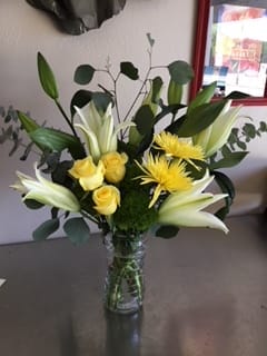 Yellow roses and white lilies in a glass vase