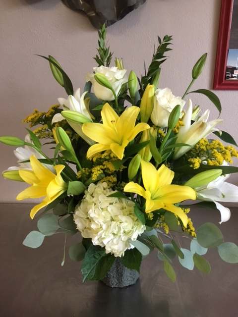 Yellow lilies and white roses in a vase with pale hydrangea