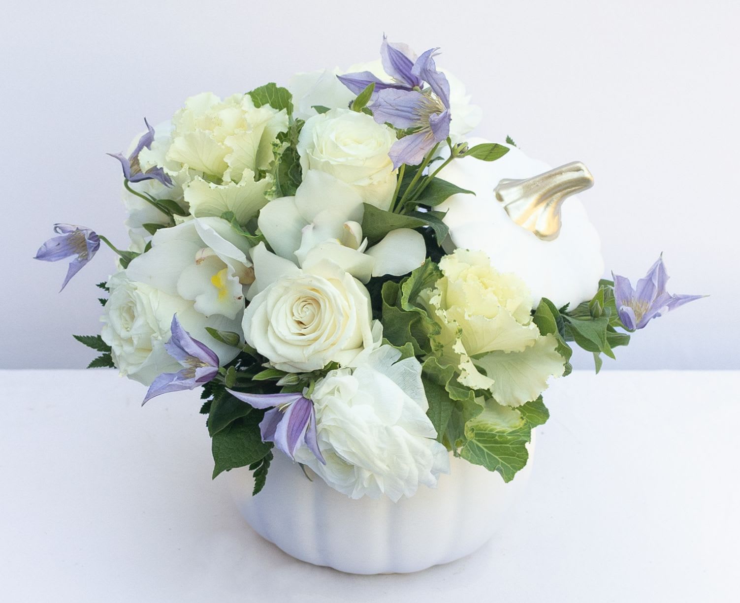 White and lavender floral arrangement in a white pumpkin-shaped container
