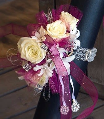 Corsage with cream roses, white flowers, and pink ribbon accents