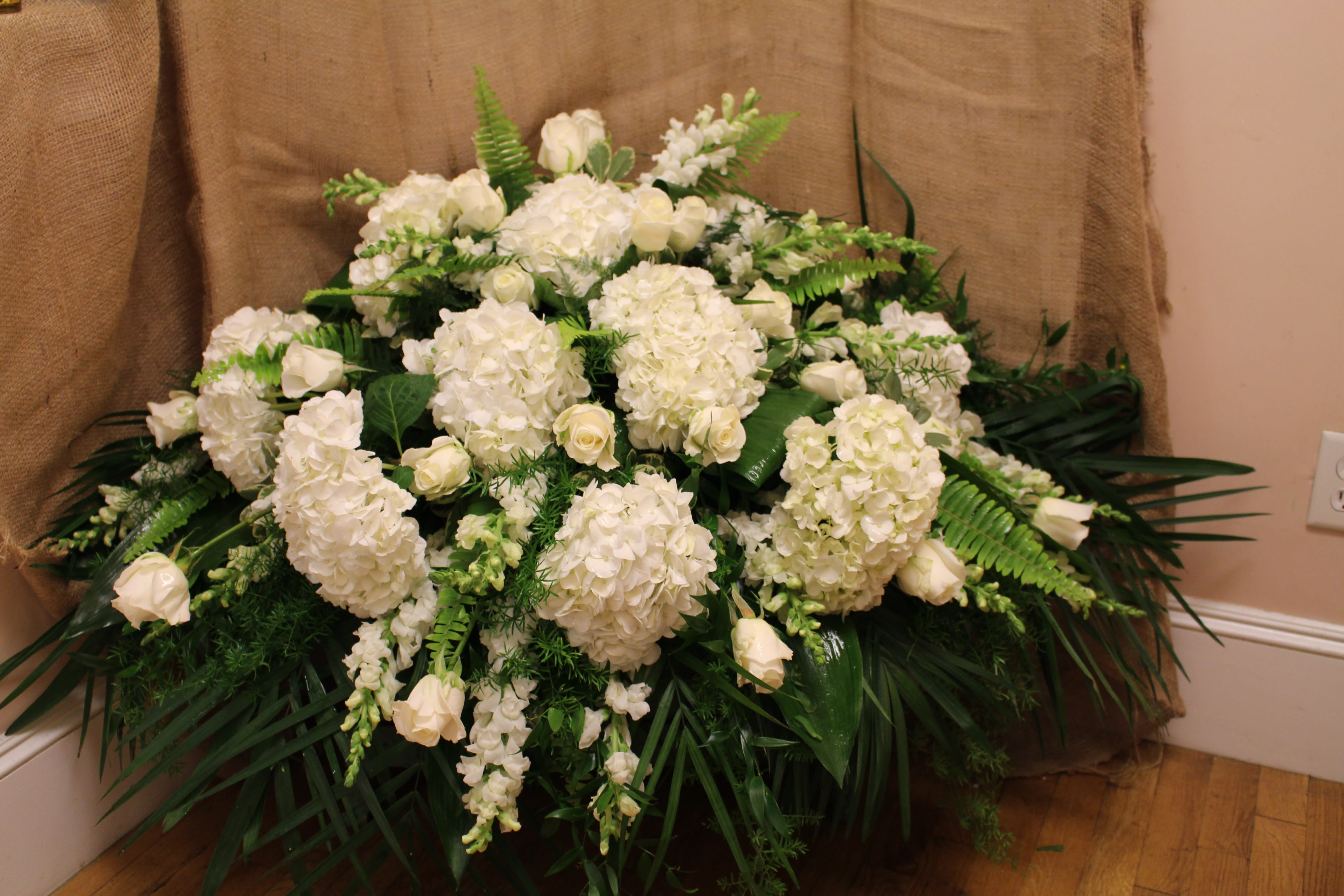 Large white floral arrangement with hydrangeas and roses
