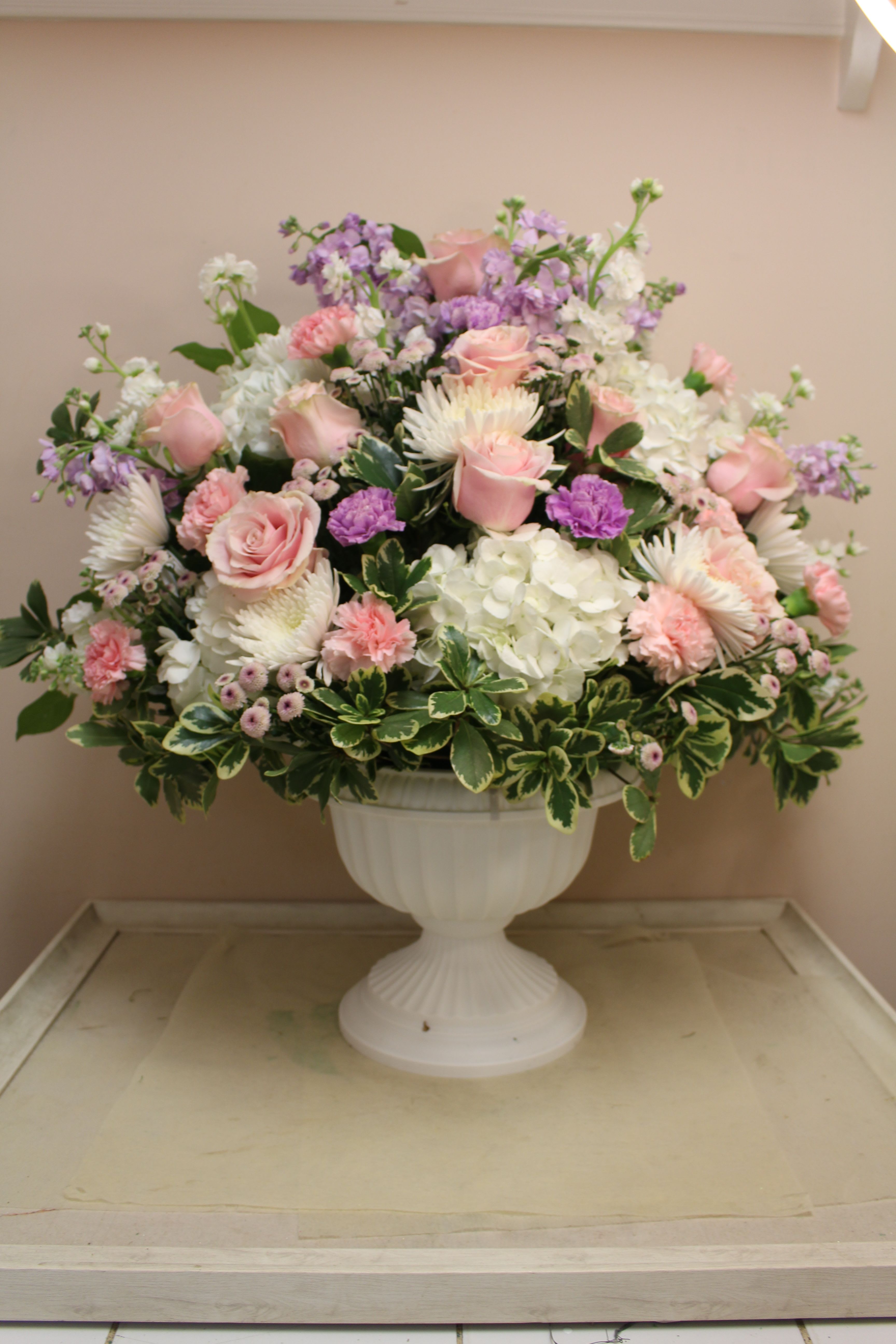 Pink and white floral arrangement in a white urn vase