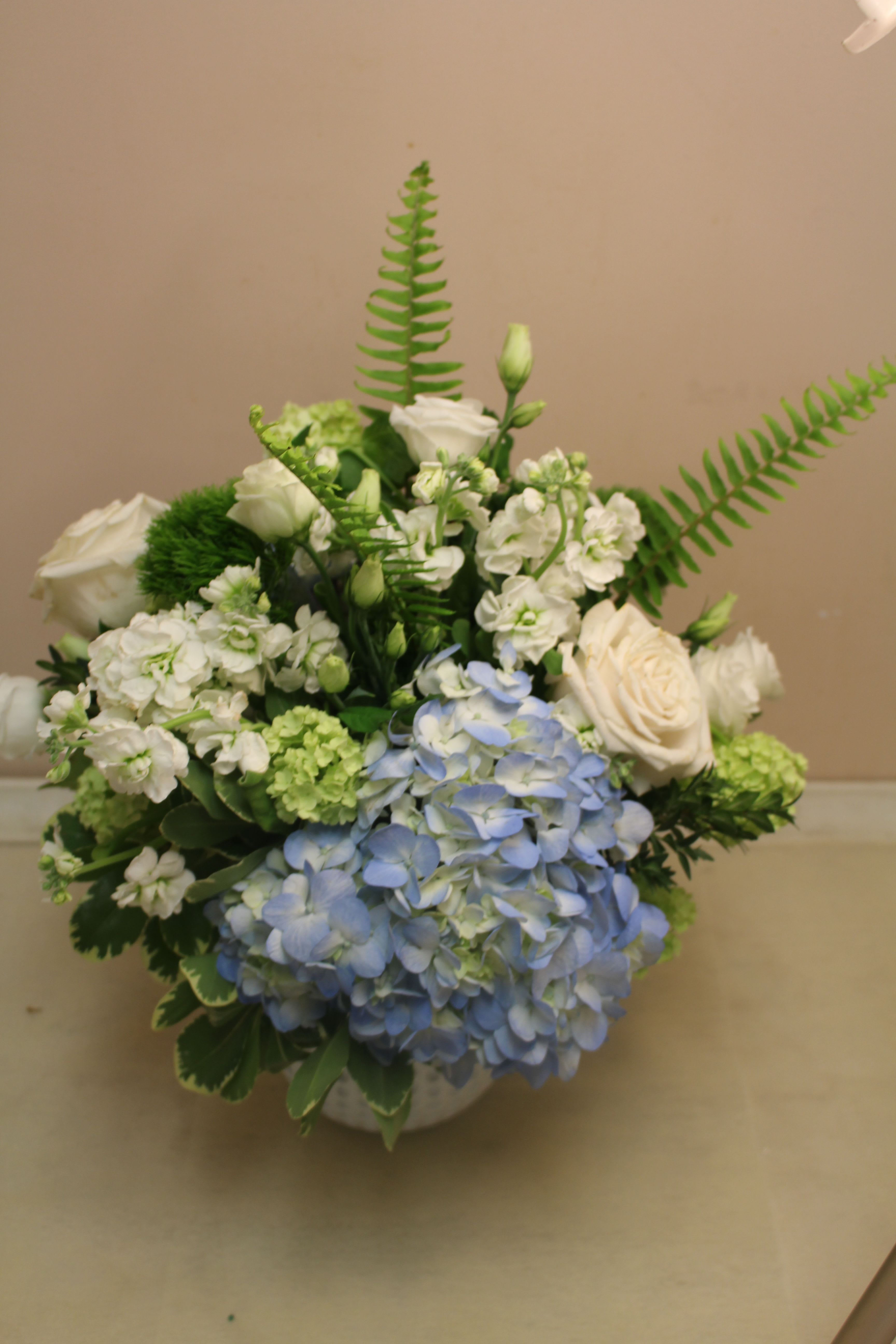 Blue hydrangeas and white roses arranged in a low vase