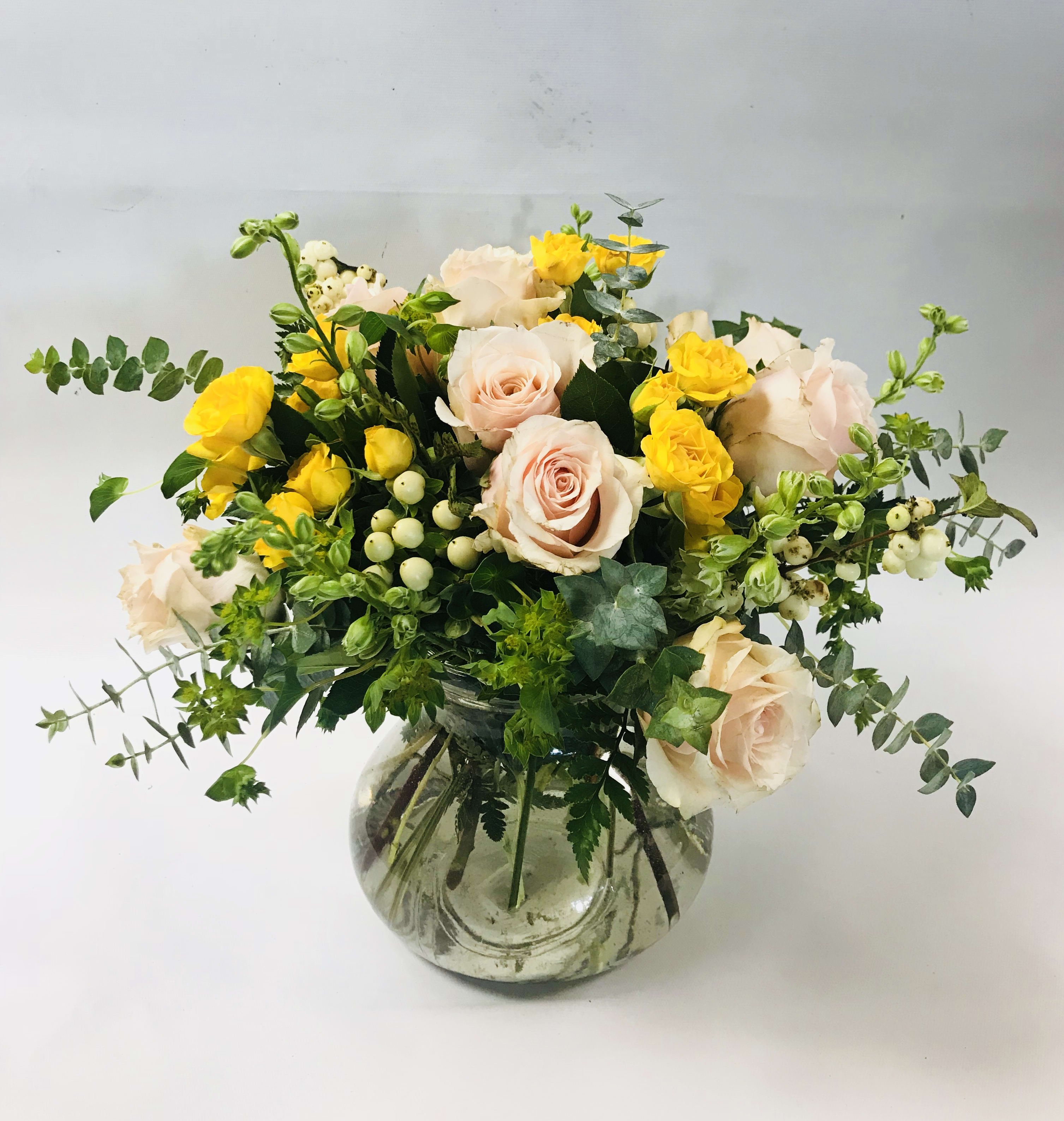 Celestial Garden - An elegant selection of peach roses, yellow spray roses, larkspur and eucalyptus for any special occasion. Standing apprx. 13" tall and 13" wide.