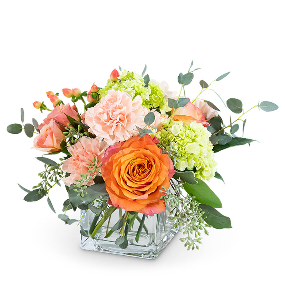 Orange roses and pink carnations in a clear square vase