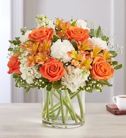Sweet Citrus™ Bouquet - The sweet citrus shades in our charming bouquet bring your sentiments to life. Loosely gathered inside a clear cylinder vase, the mix of vibrant orange and creamy white blooms makes special milestones and everyday moments even more memorable.  The arrangement with orange roses and Peruvian lilies (alstroemeria); white carnations and stock; accented with baby’s breath and assorted greenery Premium arrangement measures approximately 16"H x 12"W Deluxe arrangement measures approximately 15"H x 11"W Standard arrangement measures approximately 13"H x 10"W Artistically designed in a clear glass cylinder vase; large vase measures 6"H; medium/small vase measures 5"H Our florists hand-design each arrangement, so colors, varieties and container may vary due to local availability To ensure lasting beauty, lilies may arrive in bud form and will fully bloom over the next few days
