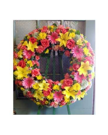 Circular wreath of pink, yellow, and red flowers on a stand
