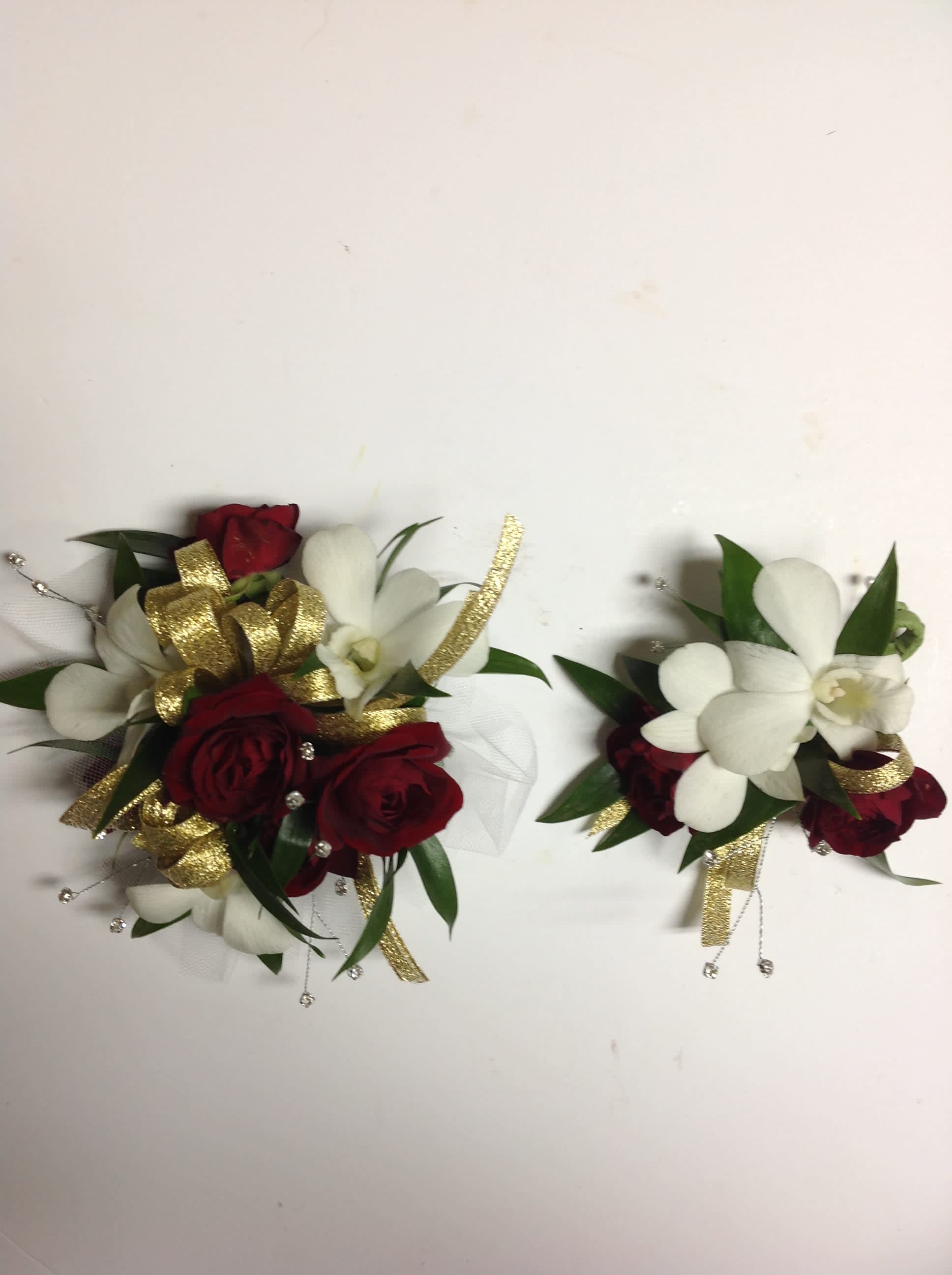 Two small floral corsages with red roses and white orchids