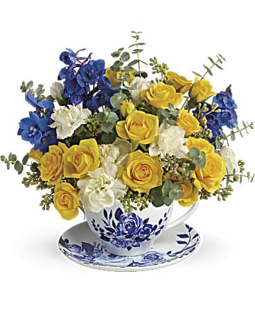 Yellow and blue rose bouquet in a teacup and saucer