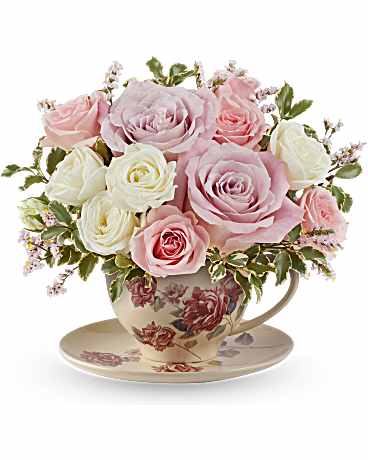 Pink and white roses arranged in a floral teacup