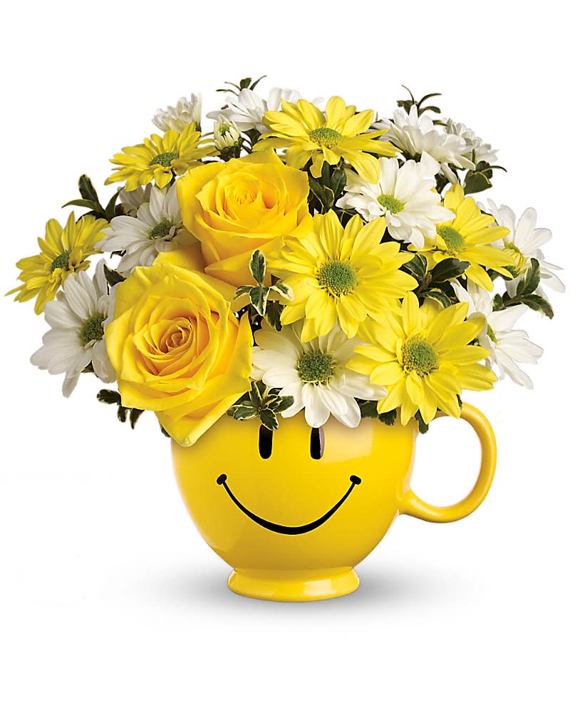 Yellow and white daisies with yellow roses arranged in a yellow smiley-face mug.