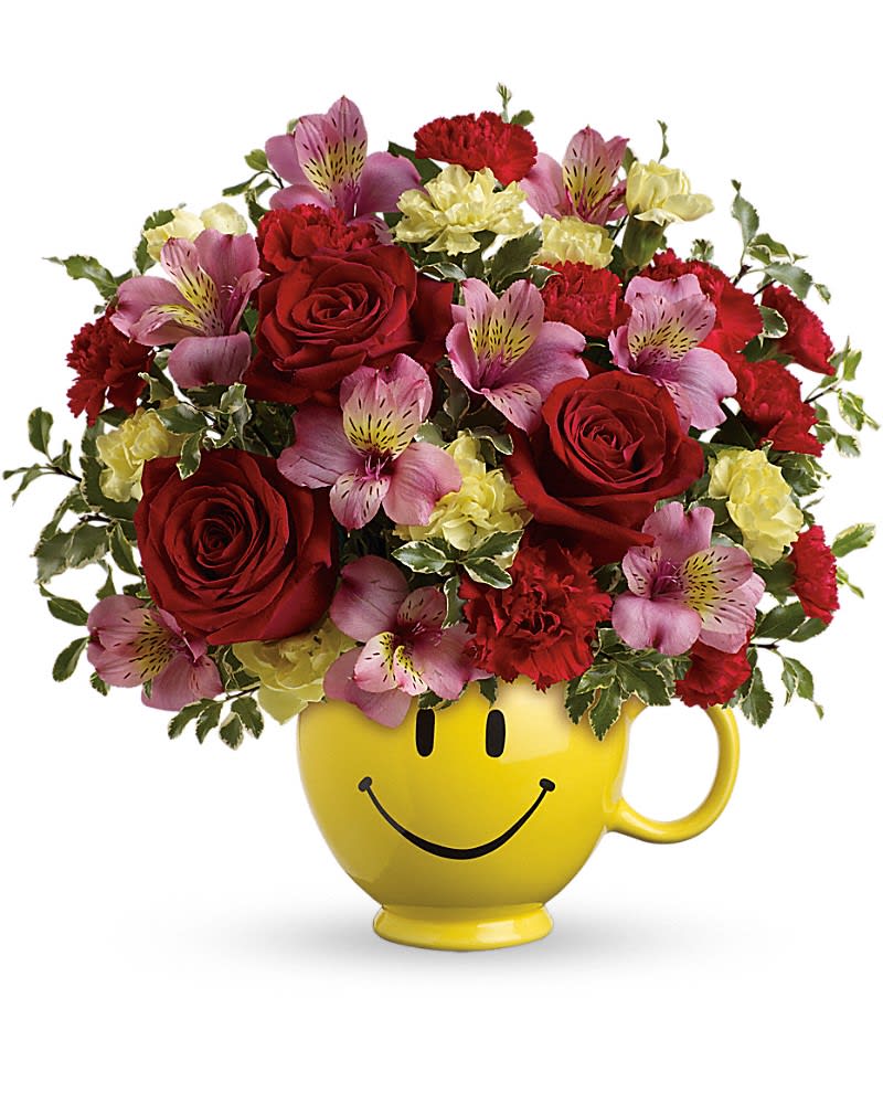 Bouquet of red roses, pink alstroemeria, and yellow carnations in a smiley-face mug