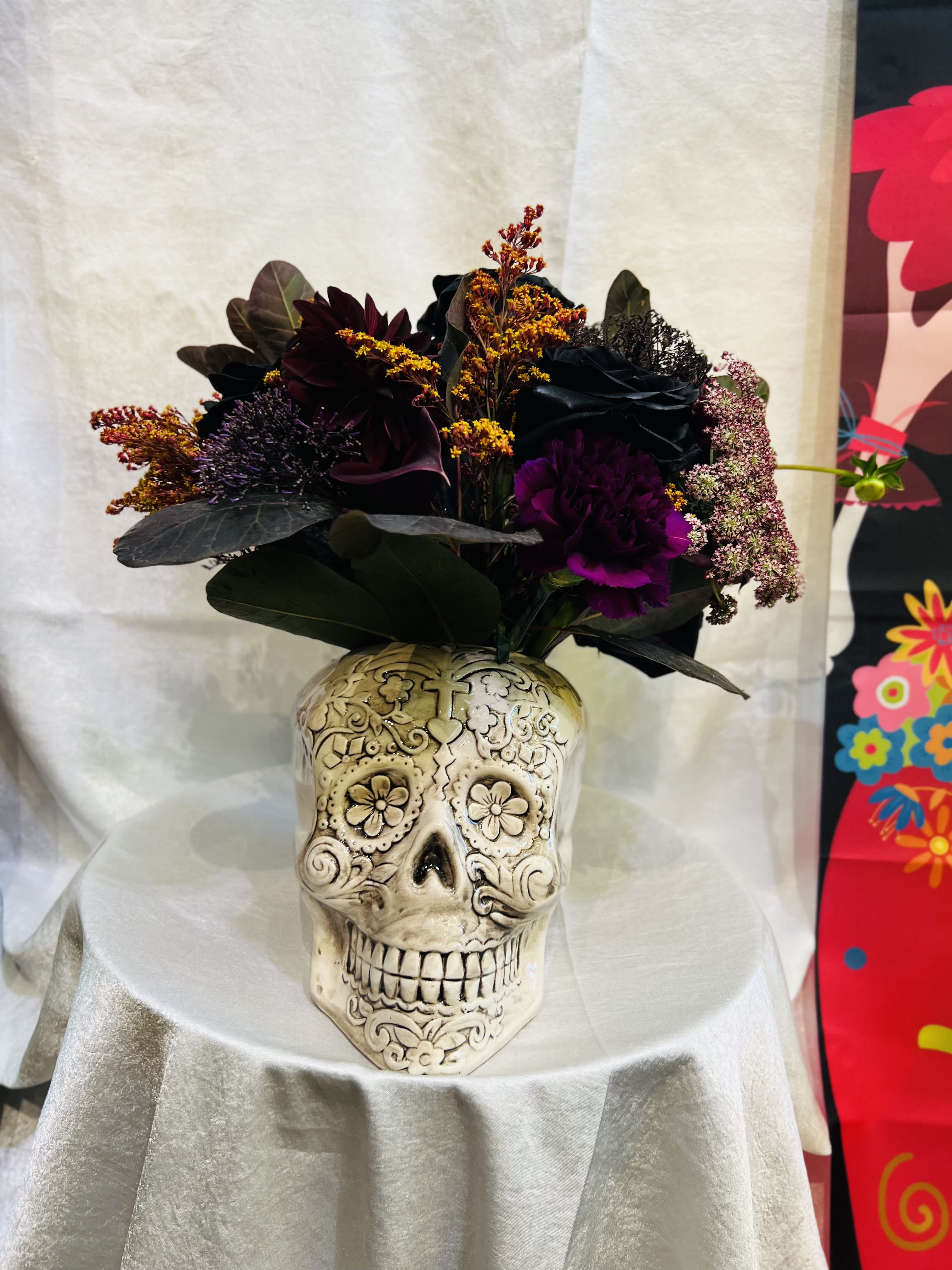 Dark floral arrangement in a decorative skull vase