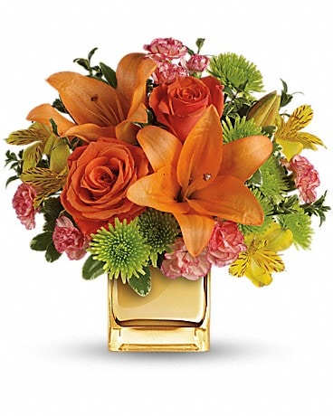 Orange lilies and roses in a square glass vase