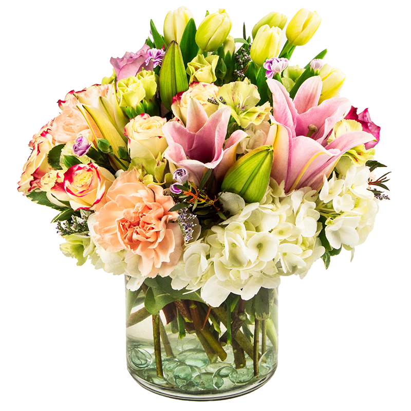 Mixed bouquet of pink lilies, roses, hydrangeas, and tulips in a glass vase