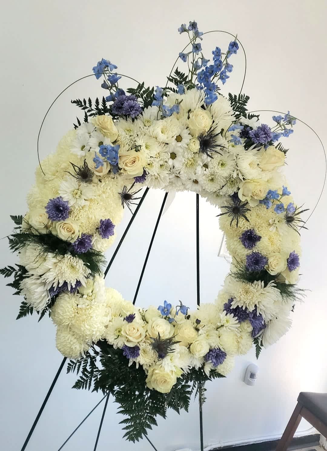 Large floral wreath of white and blue flowers on a black stand