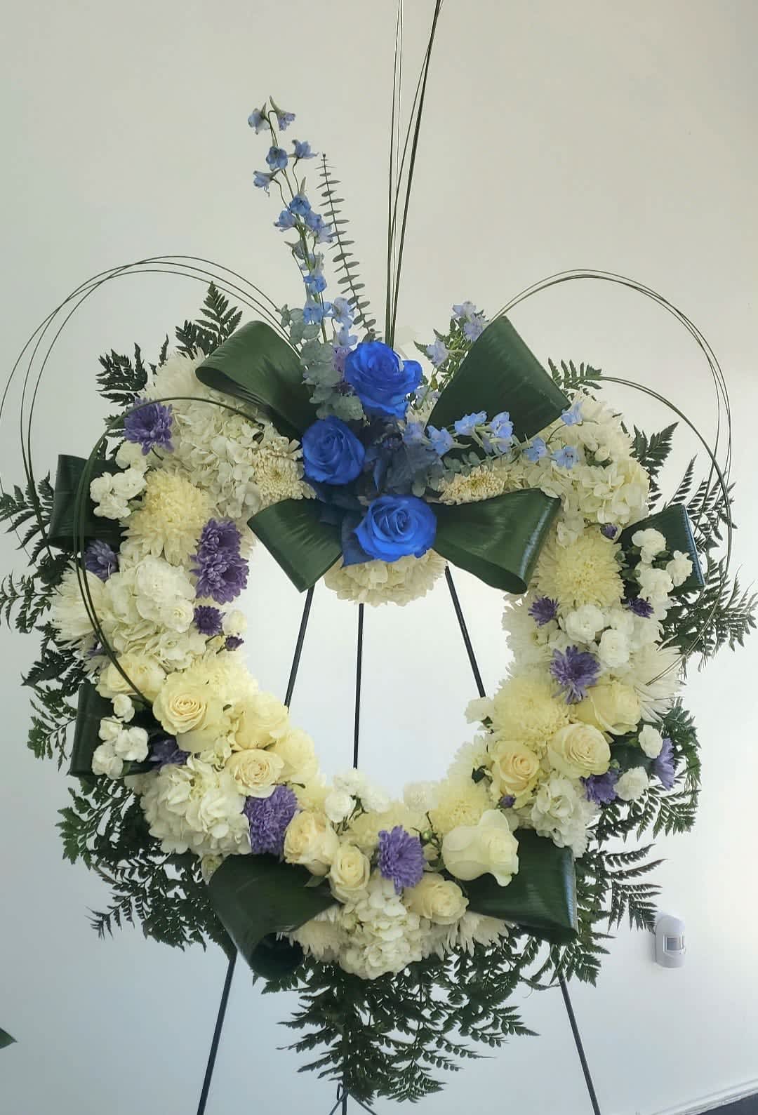 Large floral wreath with blue and white flowers on a stand