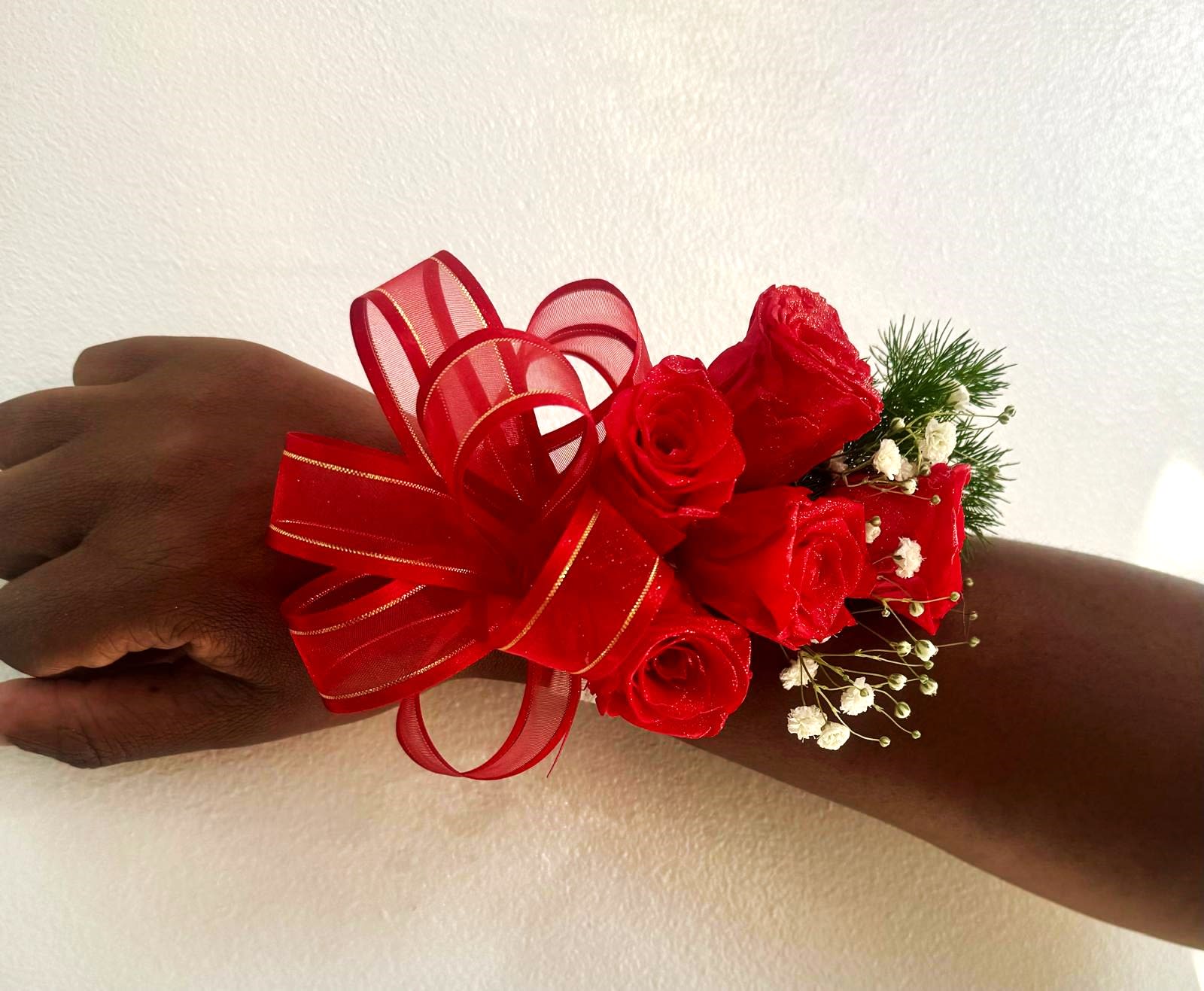 Red rose wrist corsage with ribbon and baby's breath