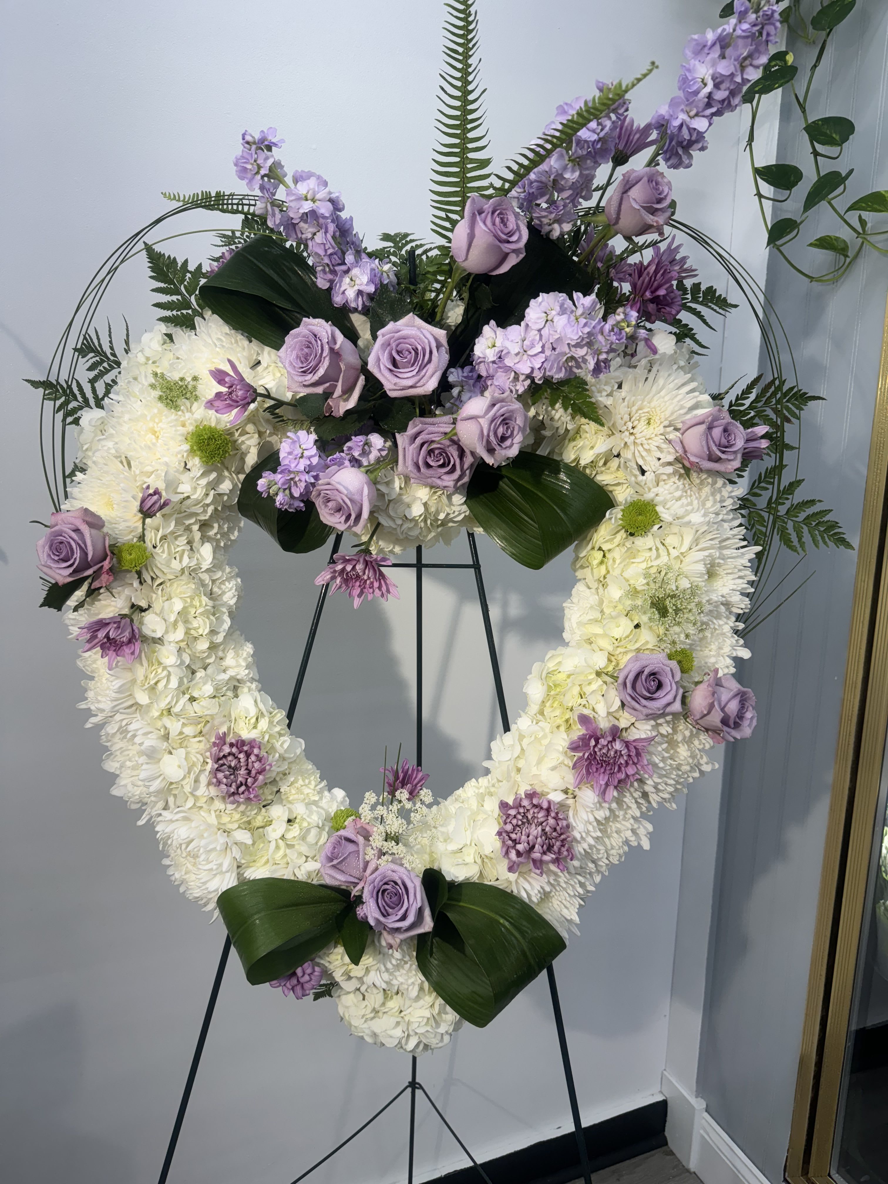 Heart-shaped floral wreath with lavender roses and white blooms on an easel