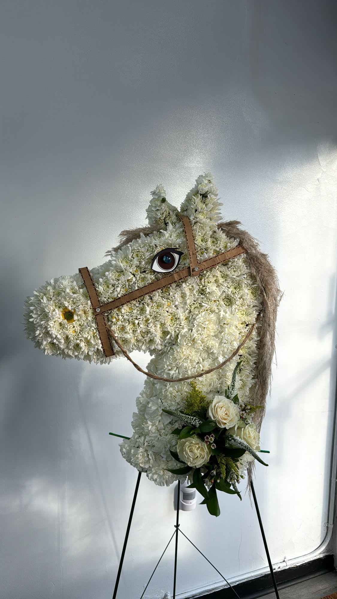 Horse-shaped floral standing display with white flowers and a small bouquet