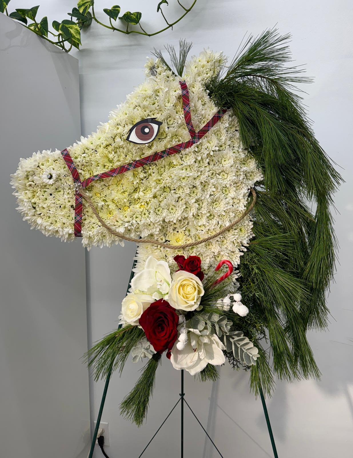 Horse-shaped floral standing spray with white blooms, red roses, and pine accents