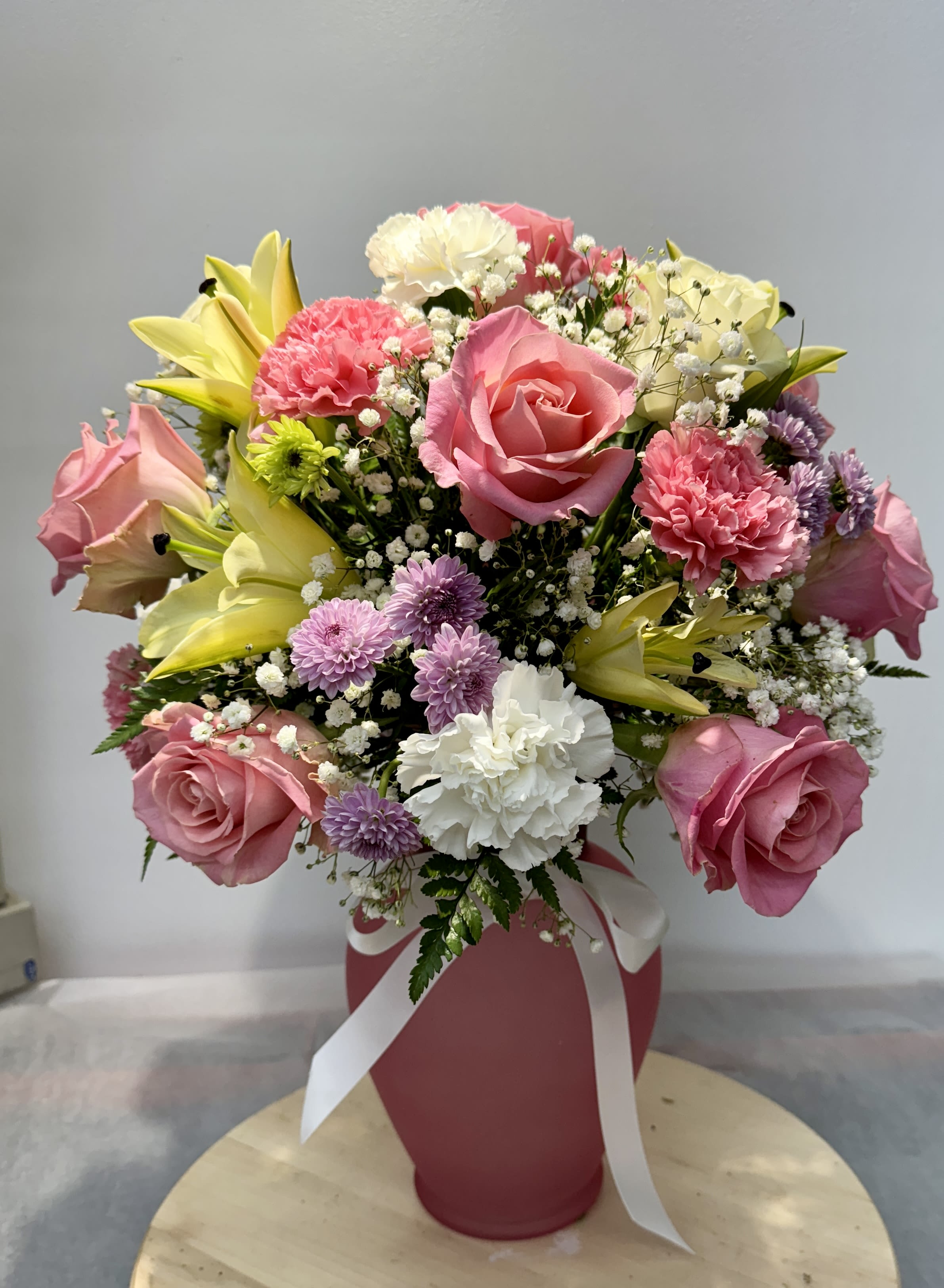 Pink and white mixed bouquet in a pink vase with ribbon