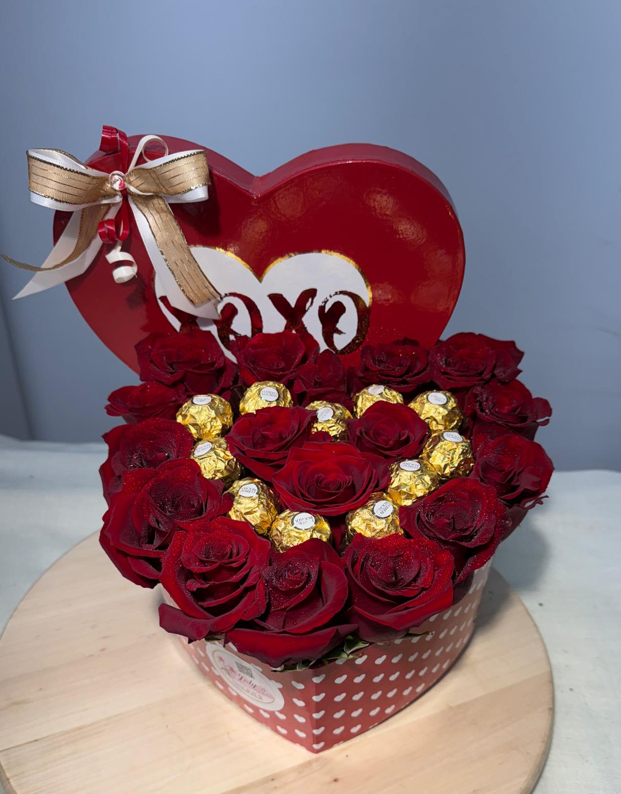 Heart-shaped box of red roses with gold-wrapped chocolates and a ribbon bow