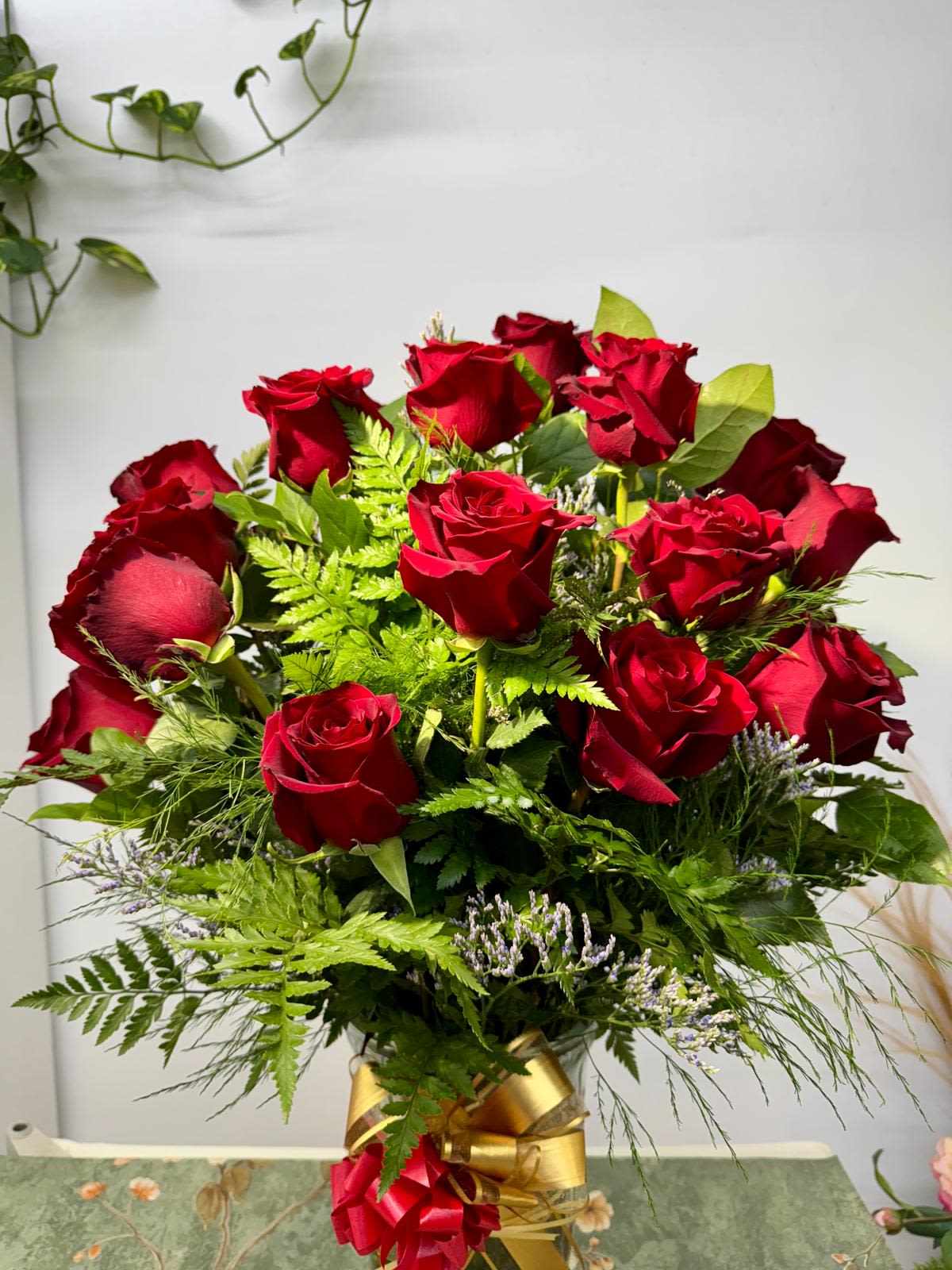 Bouquet of red roses with greenery and a gold ribbon