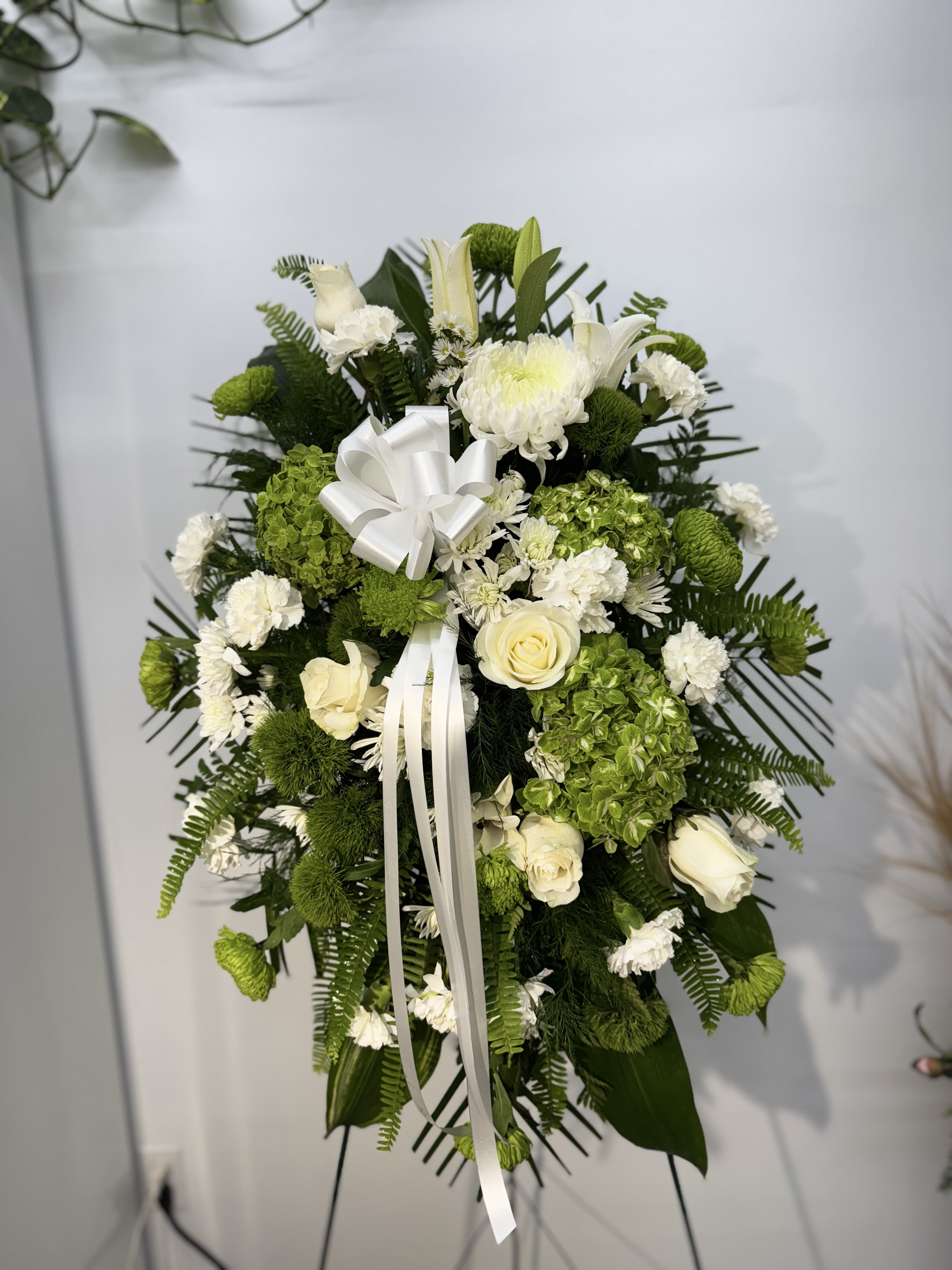 White and green funeral spray with roses and chrysanthemums on a stand