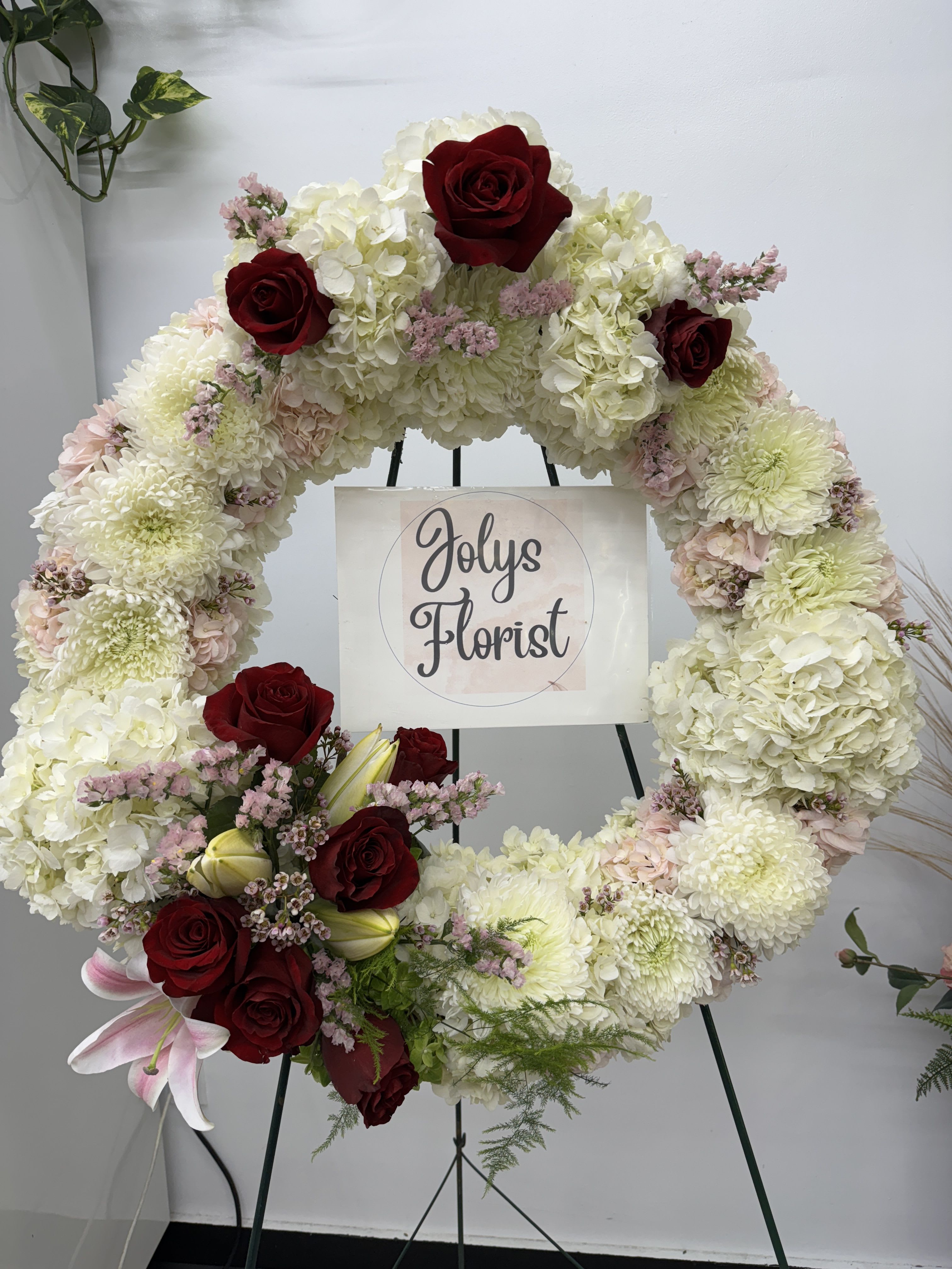 Large floral wreath with white blooms and red roses on an easel