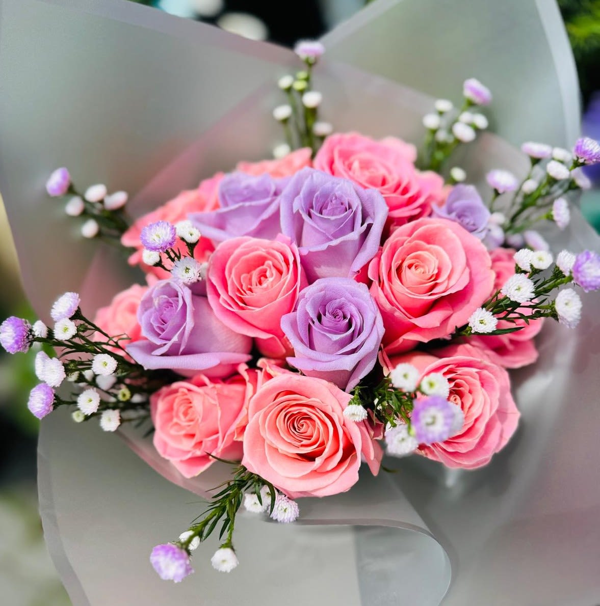 Bouquet of pink and lavender roses with small white filler flowers