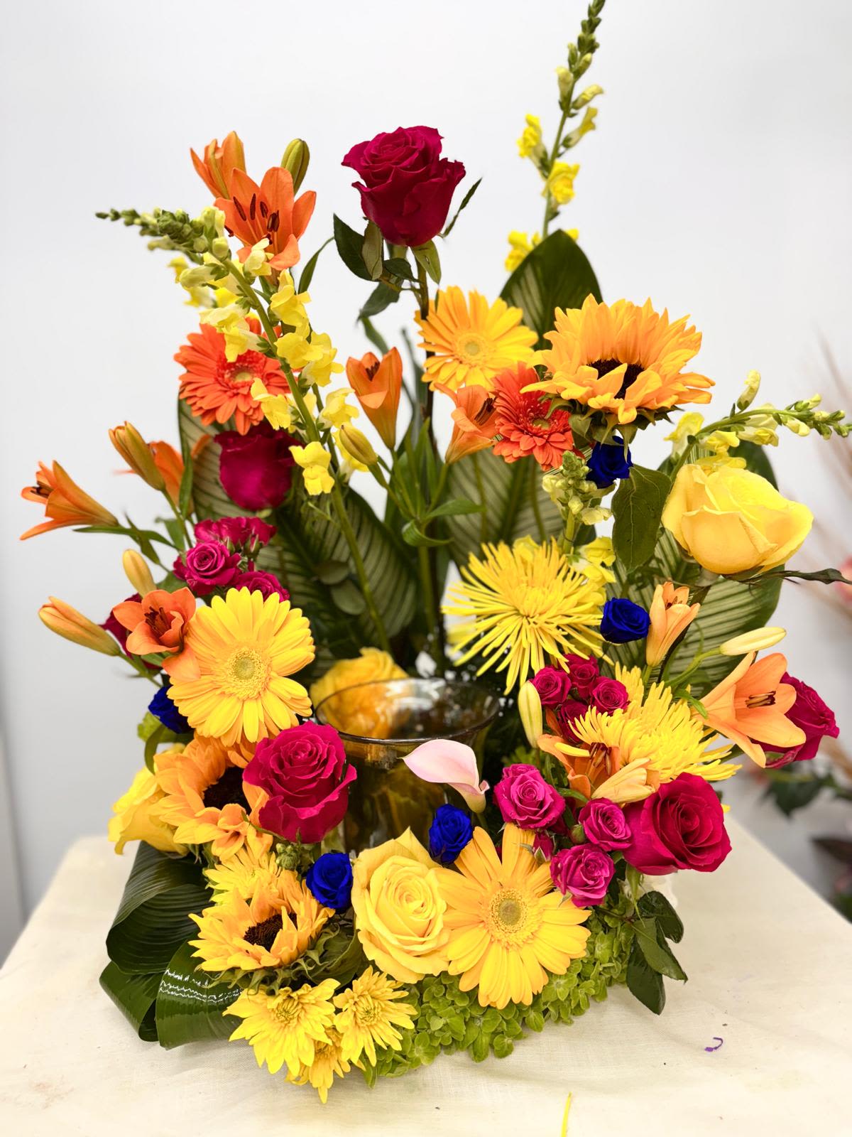 Bright mixed bouquet with roses, lilies, gerberas, and sunflowers in a vase