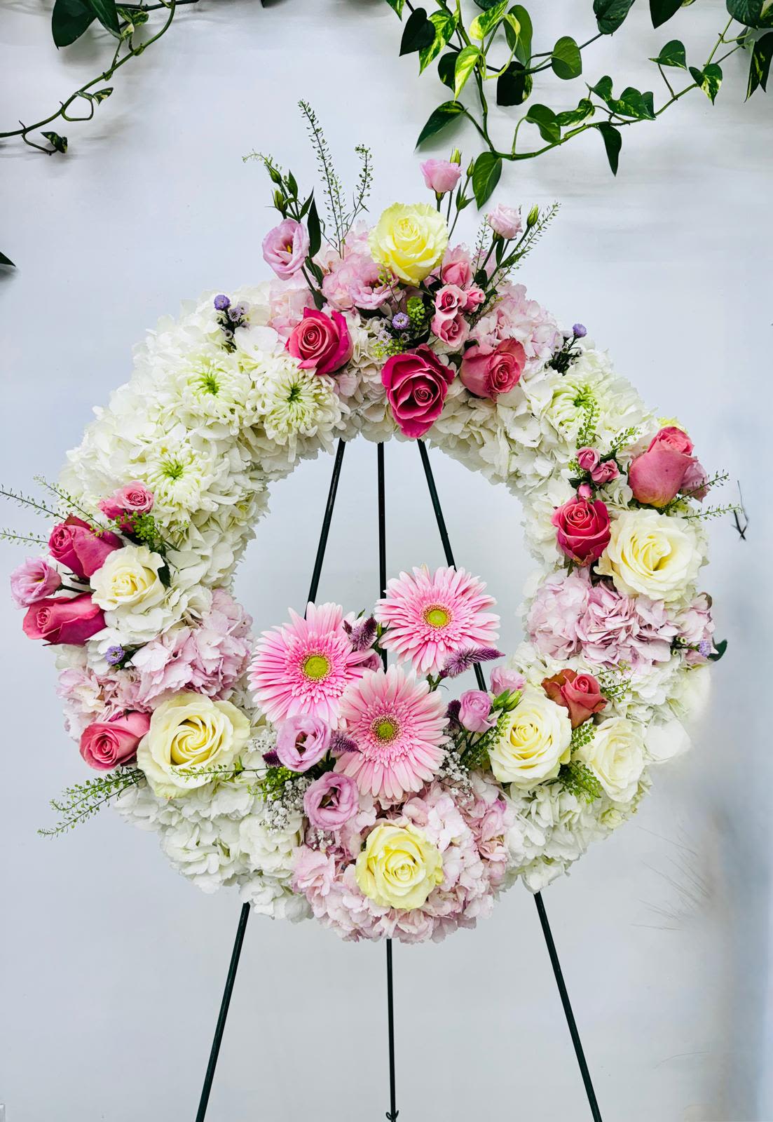 Floral wreath on a black stand with pink and white flowers