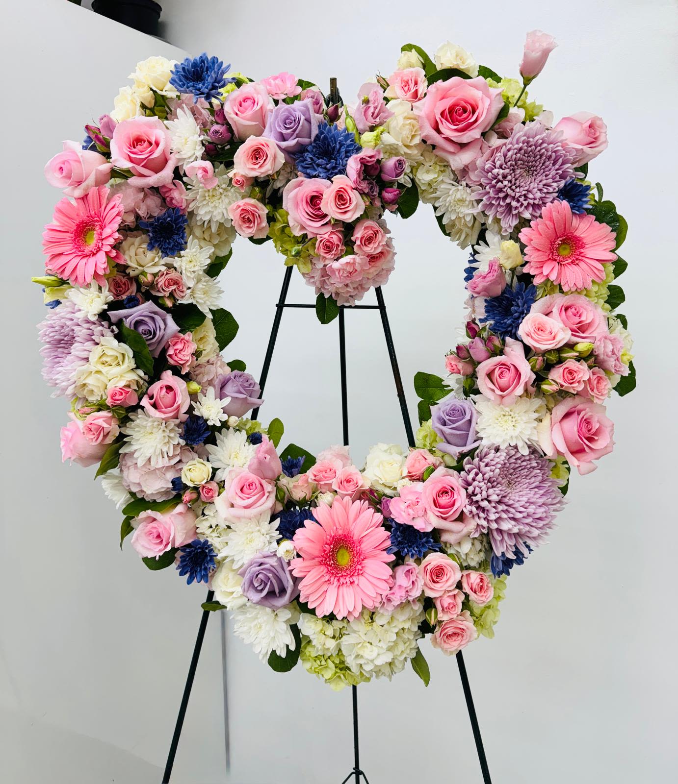 Heart-shaped floral wreath with pink, white, lavender, and blue blooms