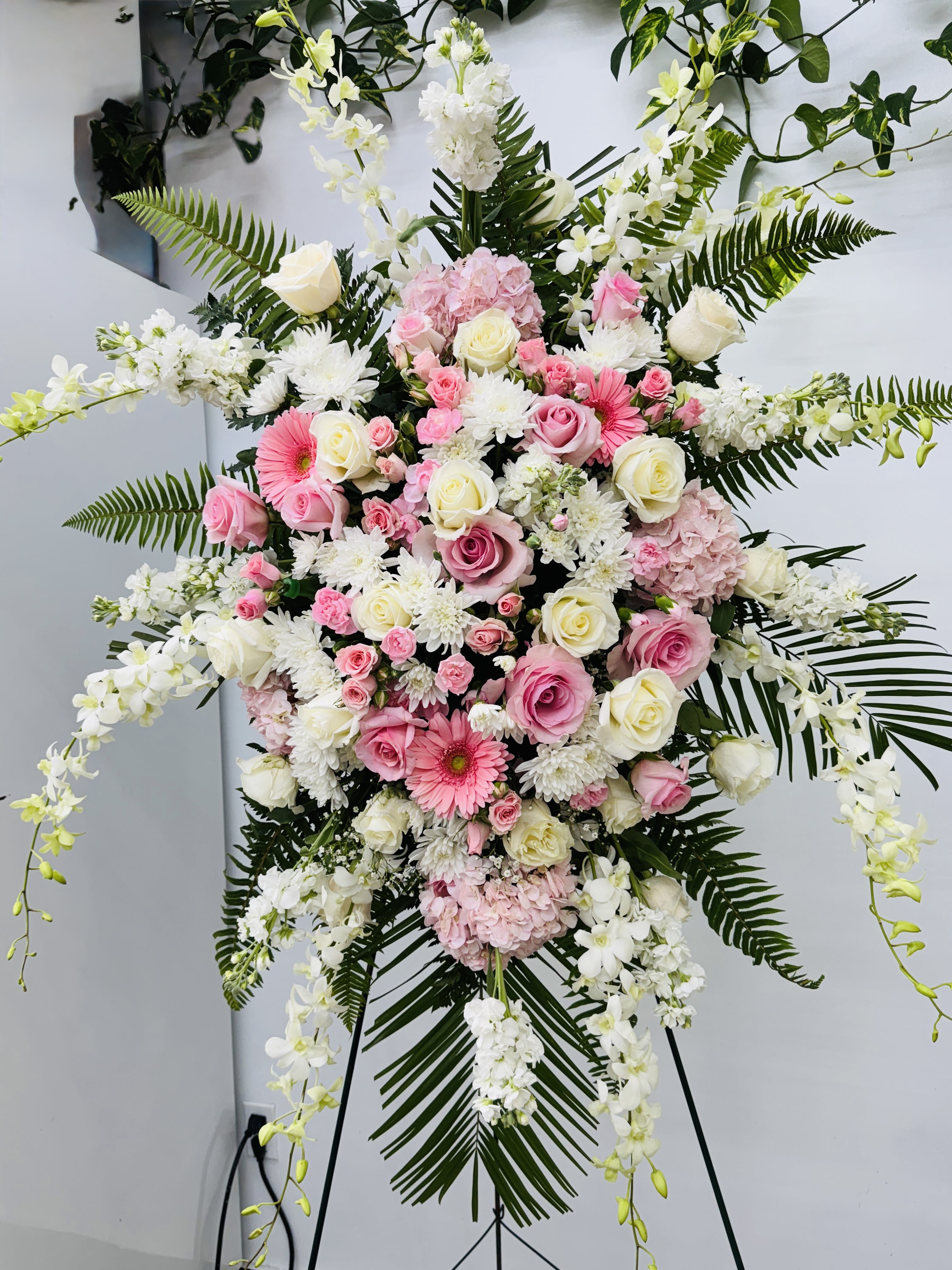 Large standing floral spray with pink and white flowers on an easel