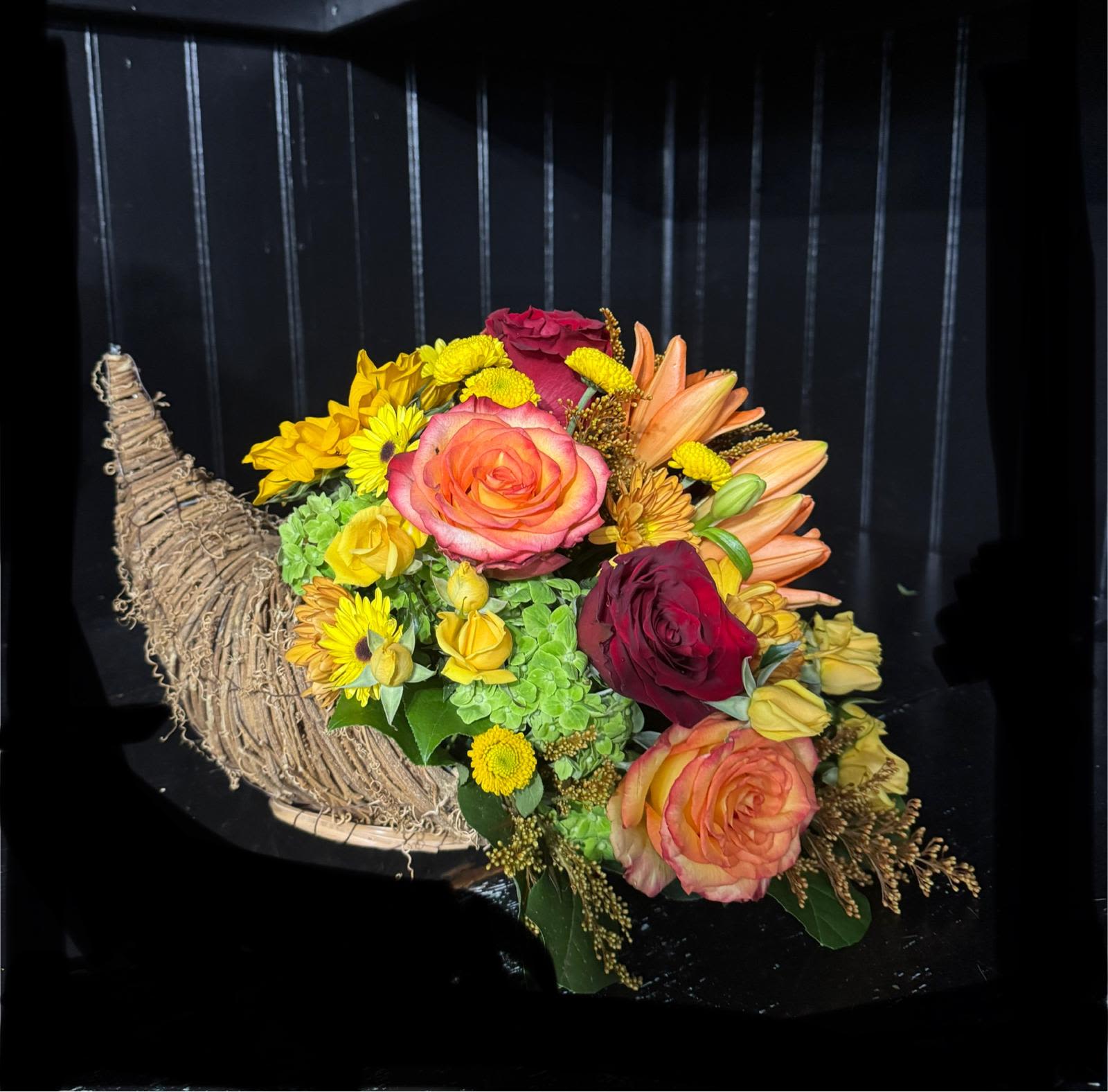 Cornucopia  Centerpiece (large) - Looking to stun your gracious host or hostess this Thanksgiving? Look no further! This gorgeous cornucopia, overflowing with brilliant orange roses, fragrant lilies and smoldering bronze daisies, is the perfect way to show your thanks this holiday season. Not only does it make a uniquely impressive gift, the Blooming Abundance Cornucopia is also a splendid way to spruce up your own living or dining room in preparation for the guests to come!