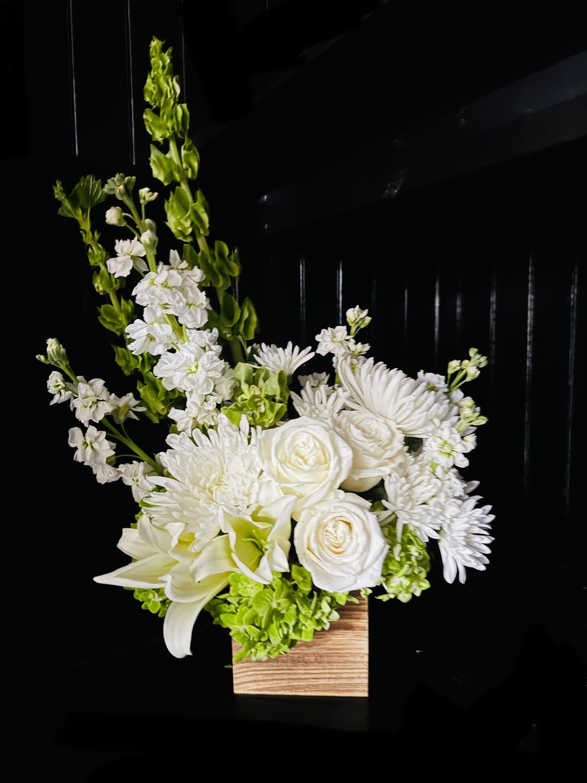 White floral arrangement in a wooden box with tall green spikes