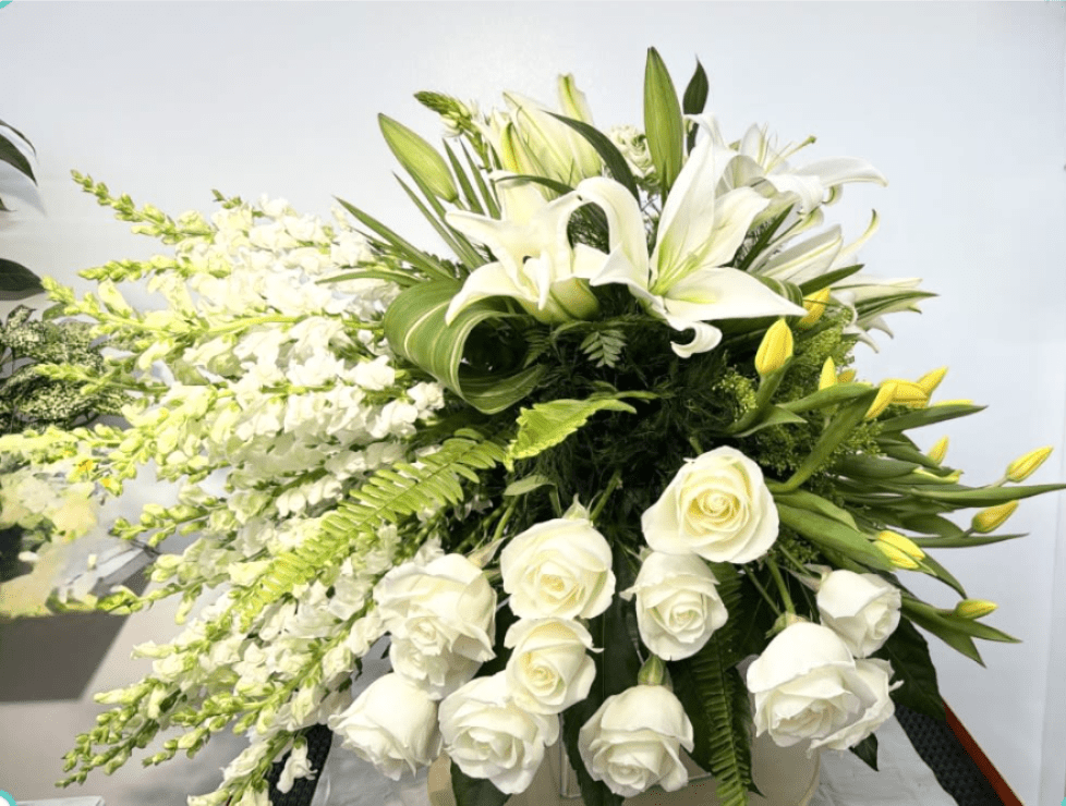 Large white floral arrangement with lilies, roses, and cascading blooms