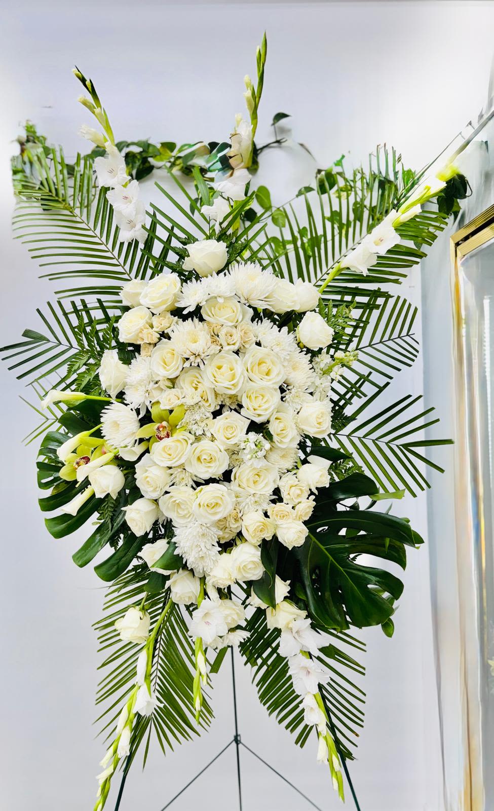 Large white floral standing spray with roses and lilies on a stand